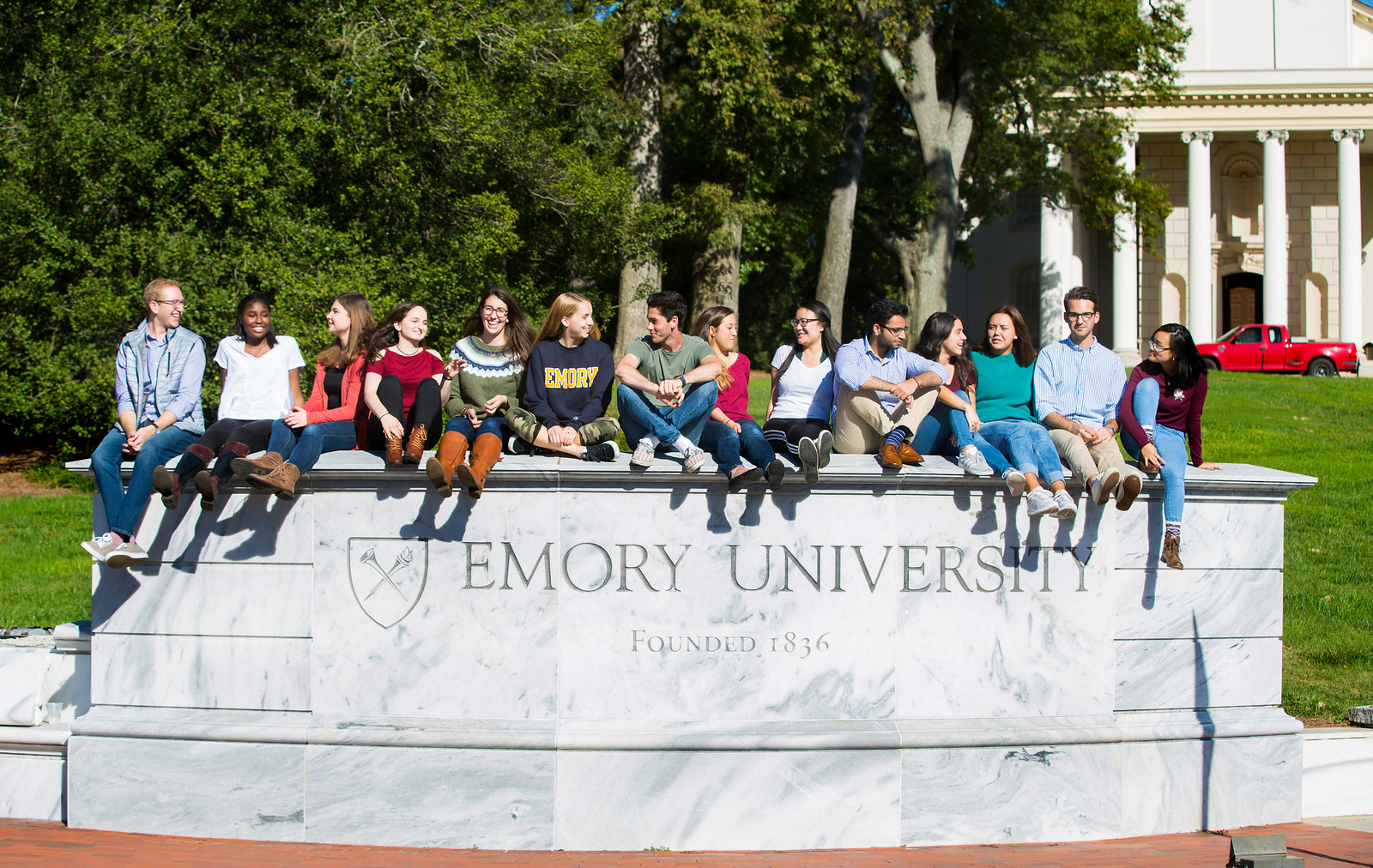 students sitting on a large stone wall that says emory university